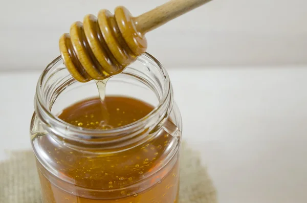 Jar of honey and a dipper — Stock Photo, Image