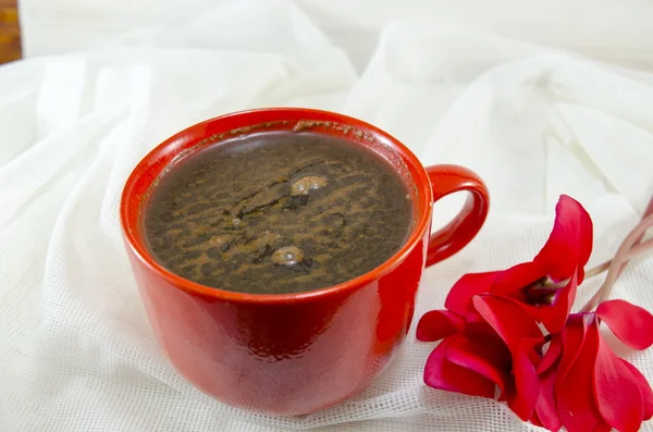 Червона чашка кави біля квітки — стокове фото