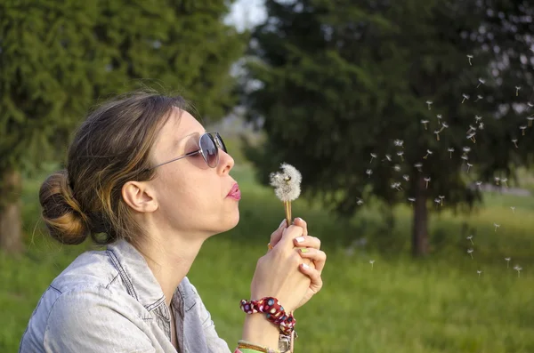 Brunetka gril dmuchanie dandelion — Zdjęcie stockowe