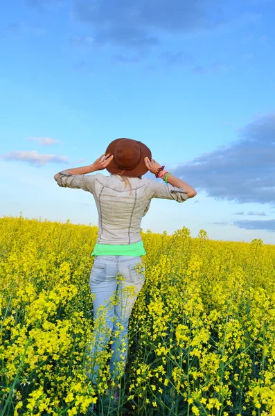 Dziewczyna patrząc na pola żółte kwiaty — Zdjęcie stockowe