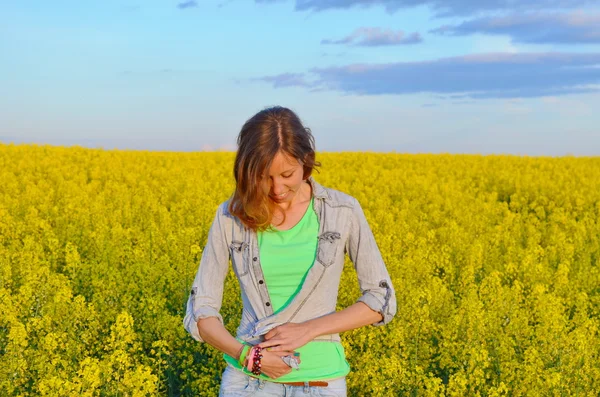 Morena abotonando su camisa en un campo de flores amarillas —  Fotos de Stock