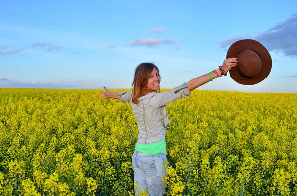 Gyönyörű lány pózol egy mező sárga virágok — Stock Fotó