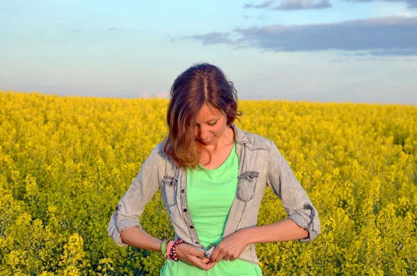 Morena abotonando su camisa en un campo de flores amarillas —  Fotos de Stock