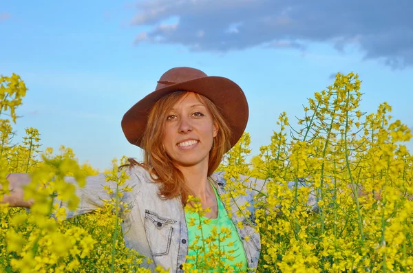 Flicka som poserar i ett fält av gula blommor — Stockfoto