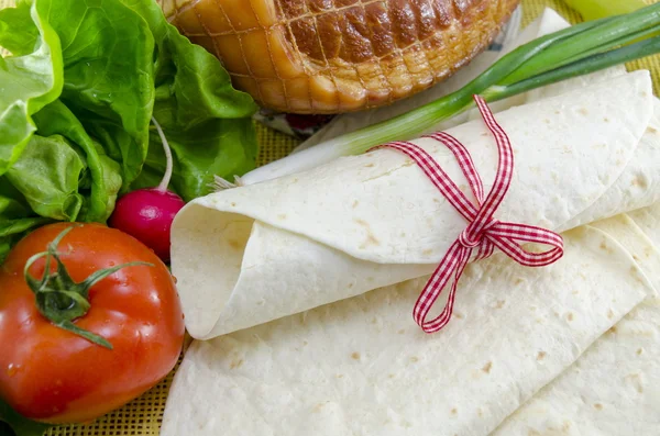 Wrapped empty tortillas on a table with tomato, lettuce and ham — Stock Photo, Image