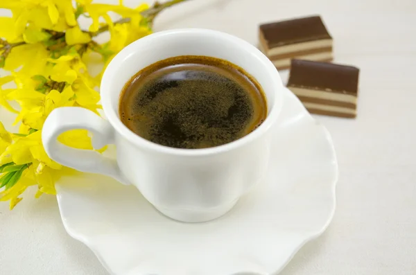 Біла чашка кави з десертом на столі, прикрашеному флоу — стокове фото