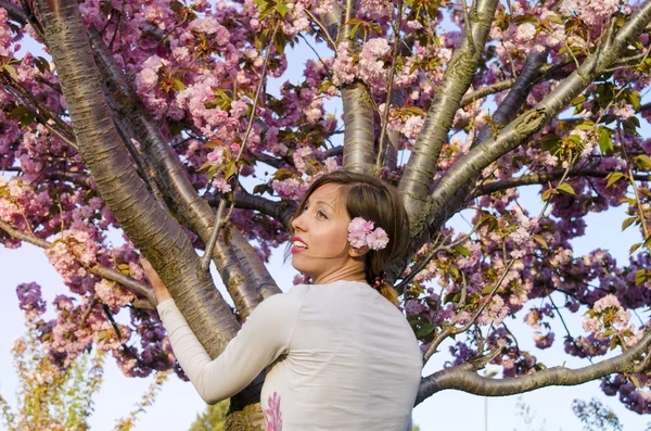 Chica joven abrazando el árbol en flor — Foto de Stock