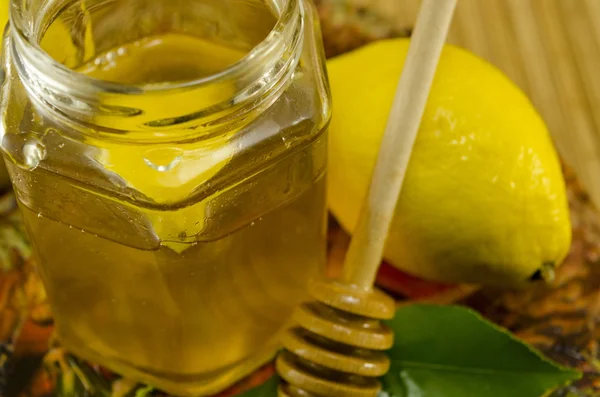 Glas Honig mit einem Holzdipper und Zitrone — Stockfoto