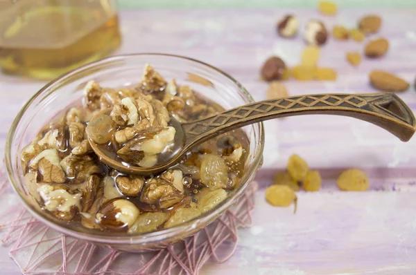 Walnuts, hazelnuts and honey in a glass dish — Stock Photo, Image