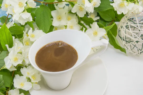 Біла чашка кави на столі прикрашена квітами — стокове фото