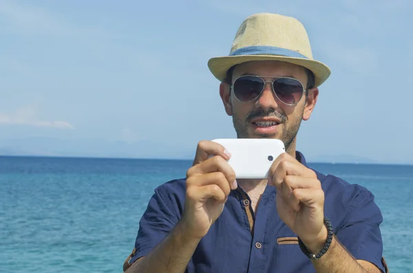 Man taking photos with his cell phone at the beach — Stock Photo, Image