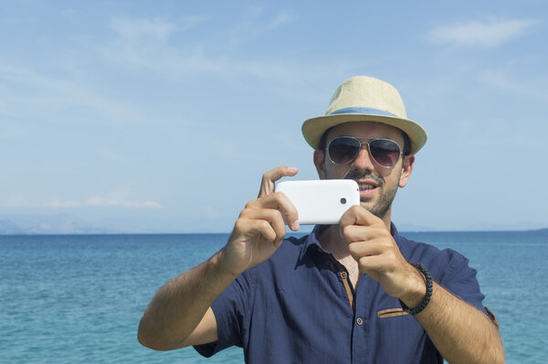 Hombre tomando fotos con su celular en la playa — Foto de Stock