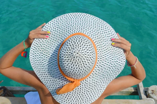 Woman wearing a white straw hat looking at the water — Stock Photo, Image