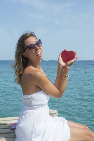 Ung kvinna med en hjärtformade låda vid havet — Stockfoto