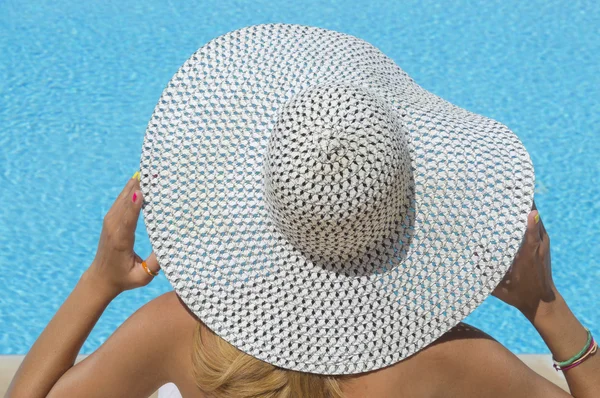 Lady with a straw hat looking at the swimming pool — Stock Photo, Image