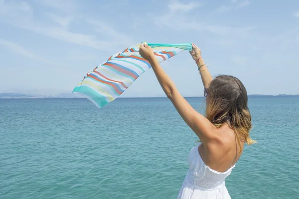 Girl waving a colourfull scarf on seaside — Stock fotografie