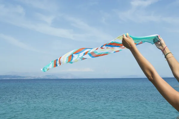 Girl waving a colourfull scarf on seaside — Stockfoto
