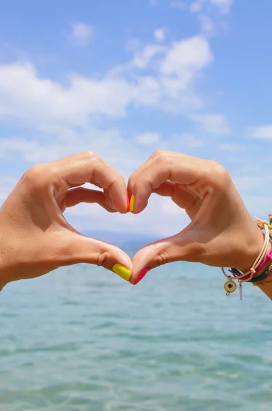 Forma de corazón hecha de manos contra el mar y el cielo — Foto de Stock