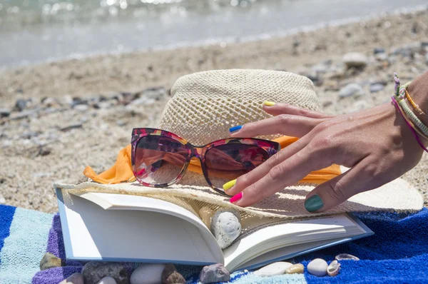 Mão meninas chegando para óculos de sol e um livro na praia com — Fotografia de Stock