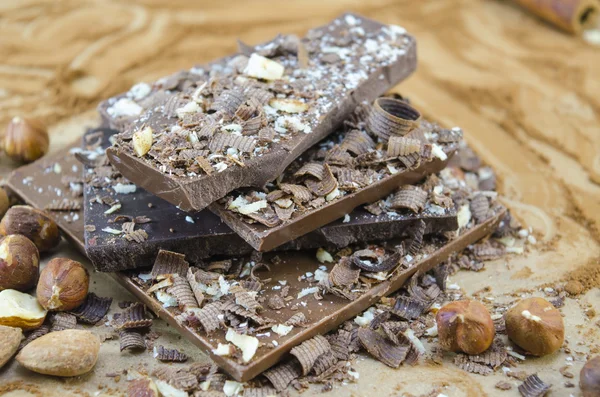 Chocolate negro apilado en una mesa de cacao espolvoreada con nueces y —  Fotos de Stock