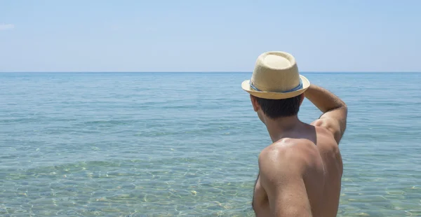 Jovem olhando para o horizonte usando chapéu de palha — Fotografia de Stock