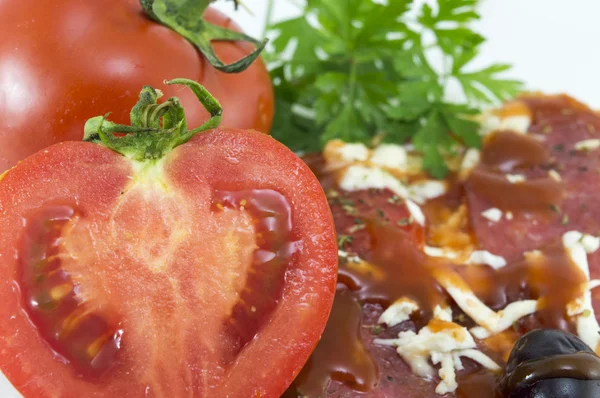 Halbierte Tomate mit Pizza und Petersilie im Hintergrund — Stockfoto