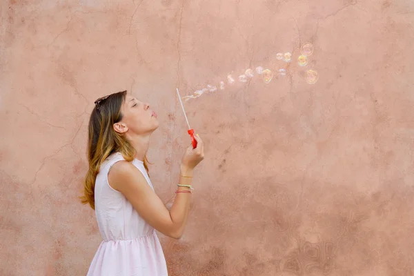 Menina soprando bolhas de sabão contra fundo colorido — Fotografia de Stock