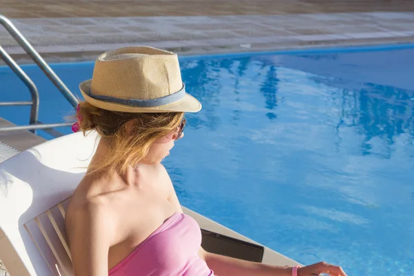 Young girl looking at the swimming pool from the sunbed. Girl at — Stock Photo, Image