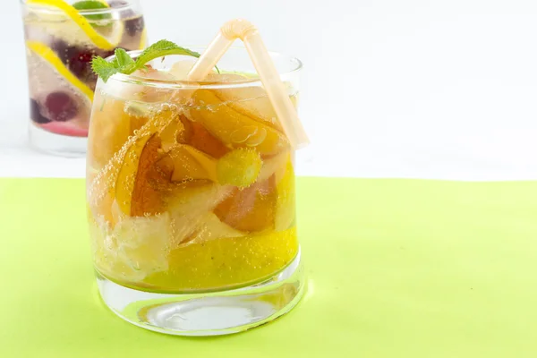 Peach juice with peach slices in a crooked glass on green backgr — Stock Photo, Image