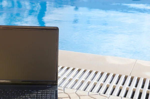 Laptop by  the pool, work on holiday concept