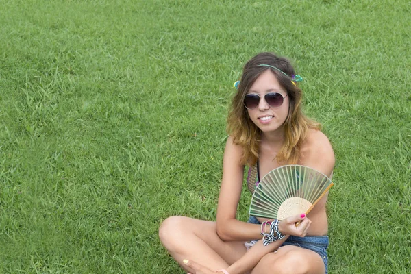 Hippy chica sentado hierba celebración ventilador — Foto de Stock