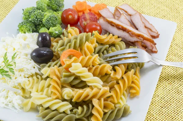 Coloured pasta served with cheese,olives broccoli, cherry tomato — Stock Photo, Image