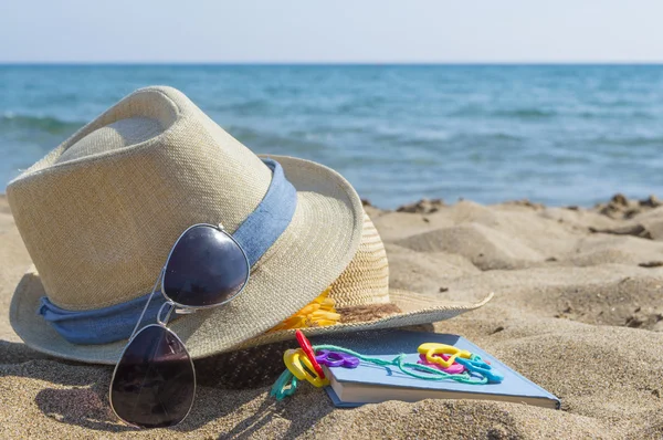 Chapéus de palha, óculos de sol e um livro na praia. Férias — Fotografia de Stock
