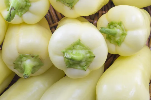 Natuurlijke groen en oranje chilipepertjes gerangschikt op een houten plat — Stockfoto