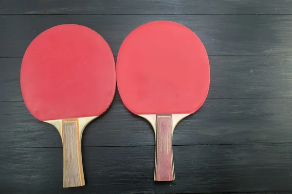 Duas raquetes de tênis de mesa vermelho no fundo escuro — Fotografia de Stock