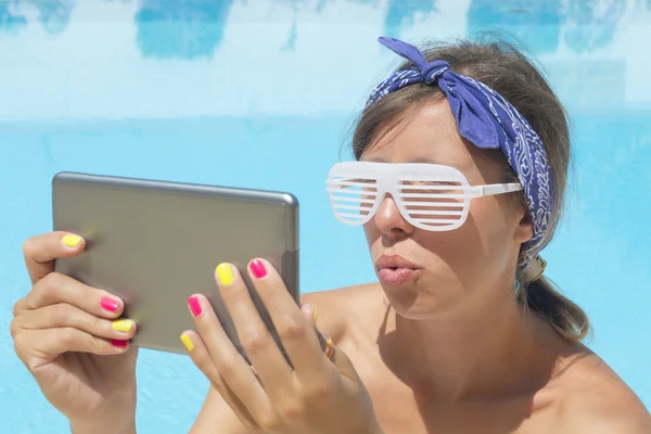 Young girl making selfie by the pool with a tablet wearing rave — Stock Photo, Image