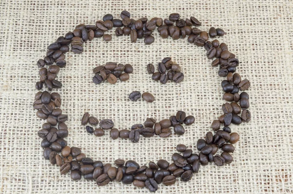 Smiley face  made entirely out of coffee grains placed on coffee — Stock Photo, Image