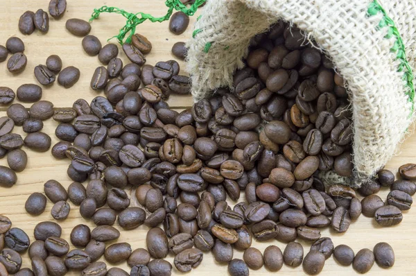 Coffee beans falling from coffee bag — Stock Photo, Image