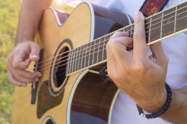 Man's hands playing acoustic guitar outdoors clipart
