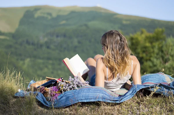 Ragazza sdraiata su una coperta e leggere un libro su un pic-nic nel f — Foto Stock