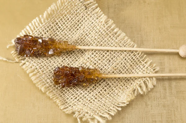Two brown sugar sticks on rustic tablecloth — Stockfoto