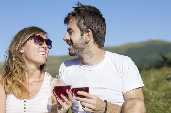 Joven pareja feliz bebiendo vino en la montaña — Foto de Stock