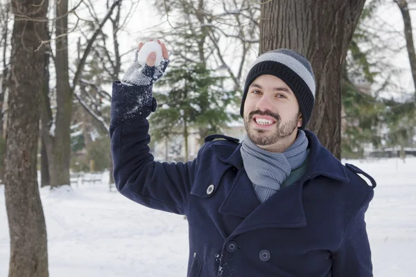 Young bearded man throwing a snowball in a park — Stock Photo, Image