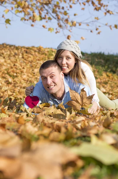 幸せなカップルの落ち葉の上に横たわる — ストック写真