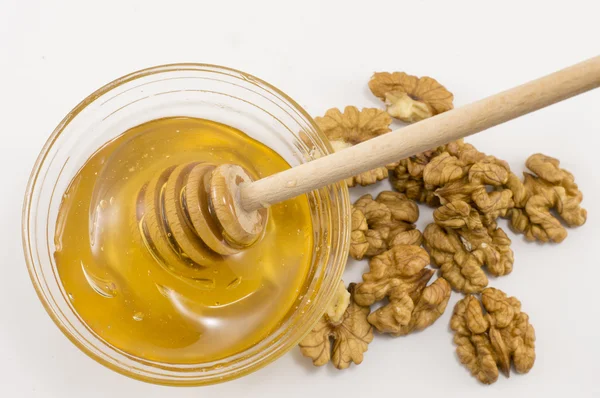 Walnuts and bowl of honey on a table — Stock Photo, Image