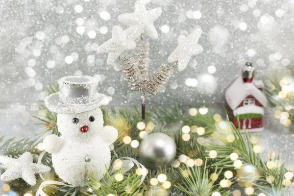 Muñeco de nieve blanco entre ramas de abeto decoradas —  Fotos de Stock