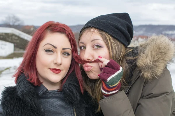 Две девушки позируют для смешного портрета зимой — стоковое фото