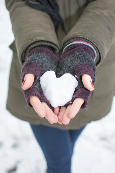 Женские руки держат сердце из снега — стоковое фото