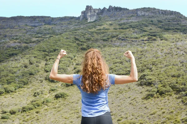 Menina flexionando músculos em um topo de montanha — Fotografia de Stock