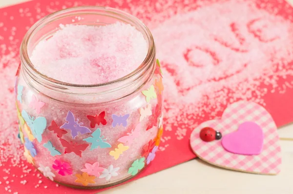 Sal de baño en un frasco junto a un corazón a cuadros rosa — Foto de Stock